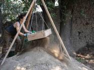 9758: Dana Zentgraf (excavator, PhD Student Christian-Albrechts-Universität Kiel) shakes soil through a sifter to look for finds that might otherwise be overlooked by the eye in the trench.