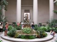 Family with children mill around the interior gardens of the West Building.