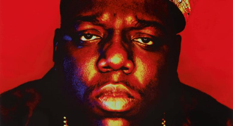 Portrait of Notorious BIG wearing a plastic crown in front of a red background