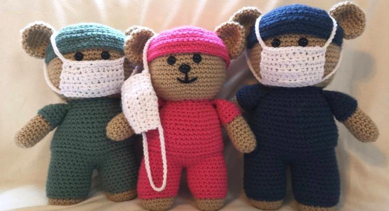 three crocheted teddy bears in scrubs and face masks