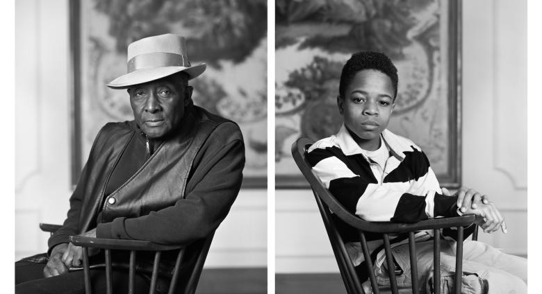 Black and white photo of seated Fred Stewart II and Tyler Collins. Both look at camera.