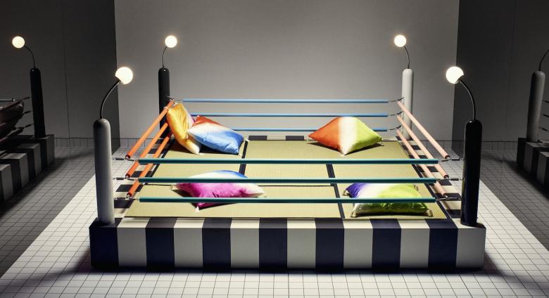 a bed or sitting area designed to resemble a boxing ring. With pillows in four corners and the ropes, lights and elevated platform of a ring.  