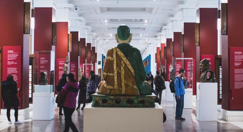 interior of a museum with large buddha and other displays, people milling about