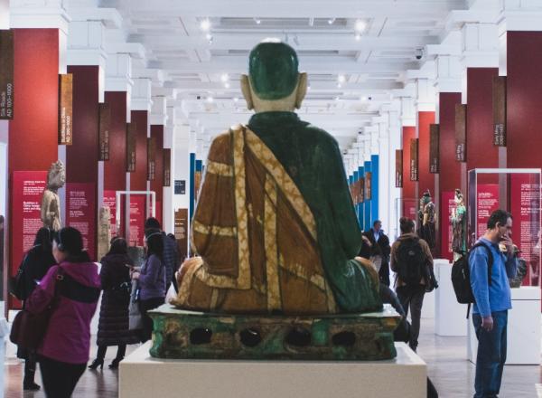 interior of a museum with large buddha and other displays, people milling about